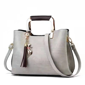 Detail of grey PU leather handbag featuring gold metal handles and cute cat pendant charm