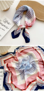 Detail of silk square scarf featuring geometric pink and blue patterns on wooden tray