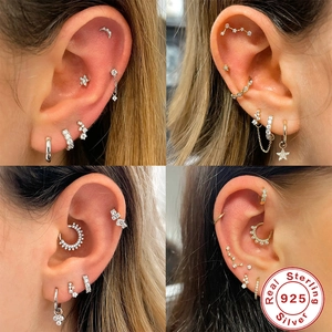 Detailed close-up of 925 sterling silver ear piercings with zircon stone settings