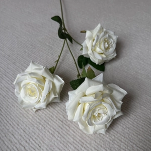 Detailed top view of three realistic white artificial roses with natural fabric petals