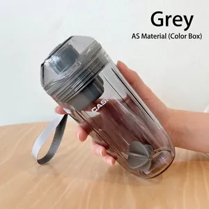 Gros plan d'un shaker transparent gris avec dragonne et boule de mélange dans la main