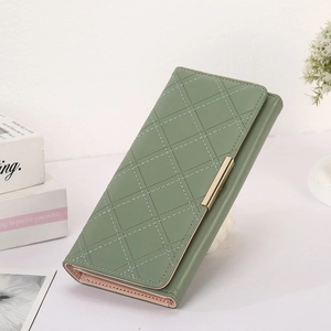 Detail of green long wallet with quilted pattern and gold metal clasp on white surface