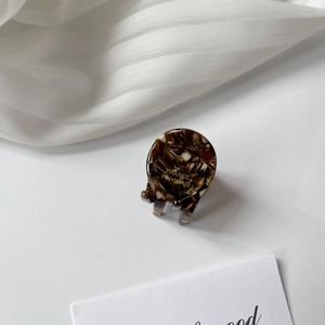 Detail of a mini acetate hair claw with brown tortoiseshell texture and gold lettering