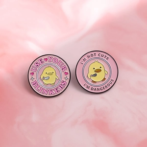 Cartoon enamel pin set with yellow duck holding a knife and funny slogans on marble background