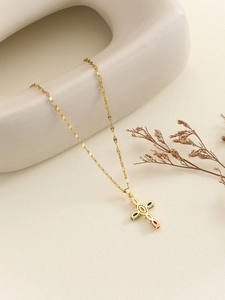 Detailed shot of golden cross necklace with colorful zircon stones on ceramic decor