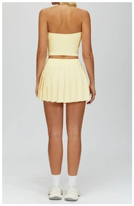 Back view of light yellow high-waist pleated tennis skirt and crop top yoga set