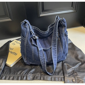 Détail d'un sac hobo en denim bleu foncé délavé avec coutures et boucle en métal réglable