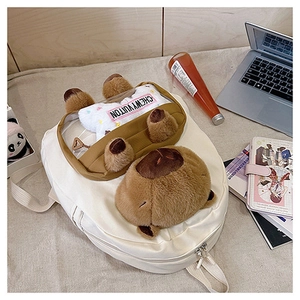 Detail of white canvas backpack featuring plush Capybara and transparent pocket window