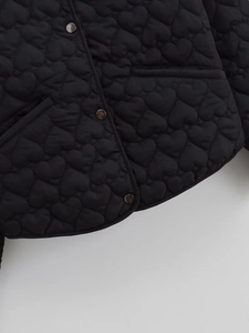 Detailed shot of black heart quilted jacket with metallic snap buttons and side pocket