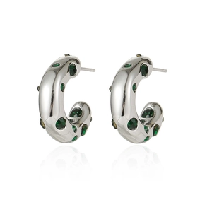 Detail of silver C-shape earrings with green zircon inlays and polished finish
