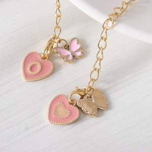 Detail of golden tumbler chain with pink heart charms, butterfly pendants, and letter O