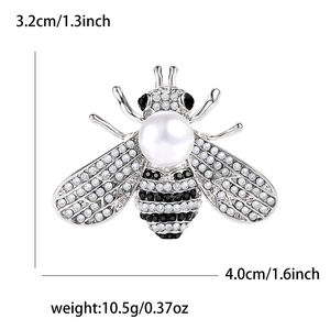 Detail showing dimensions of bee brooch with pearls and rhinestones on white background
