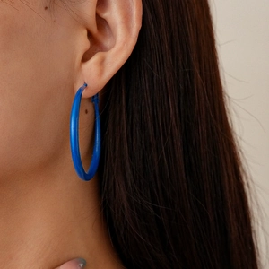 Close-up of model wearing bold Klein blue circular drop earrings with a matte finish