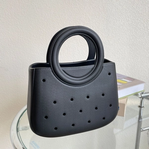 Détail d'un sac de plage noir en EVA avec poignée ronde et motifs ajourés perforés