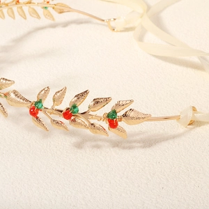 Detail of golden metal leaf headband with red and green berry beads and satin ribbon