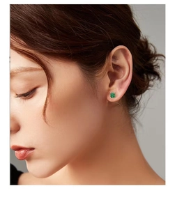 Close-up of vintage square emerald stud earrings worn by a model for a luxury look