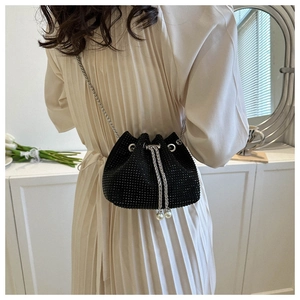 Detail of black rhinestone bucket bag with silver chain and pearl charms on a model
