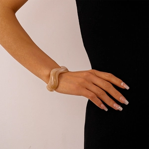 Detail of light brown marble-textured wavy acrylic cuff bracelet worn by a model