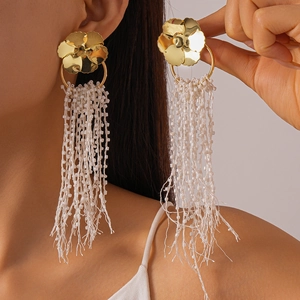 Detailed view of large white beaded fringe flower earrings with golden floral studs