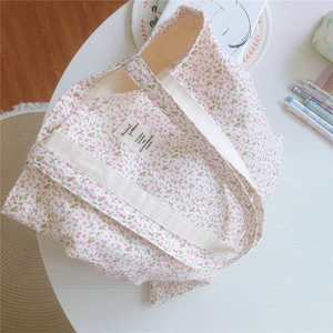 Detailaufnahme einer geblümten Baumwolltasche mit rosa Blüten und gewebtem Griff