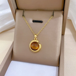Luxurious gold titanium necklace with amber stone displayed in a premium beige jewelry box