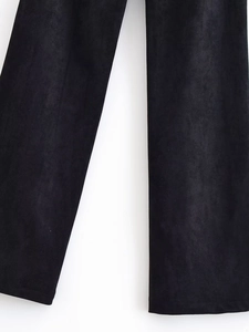 Detail view of black flared trousers showing rivets and brushed suede-like fabric texture