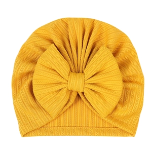 Detail of baby turban with large bow in ginger yellow ribbed elastic fabric