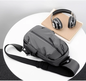 Detail view of water-resistant dark gray nylon chest bag on desk with lifestyle accessories