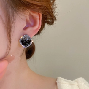 Macro detail of geometric square crystal earrings with rhinestone border worn on ear