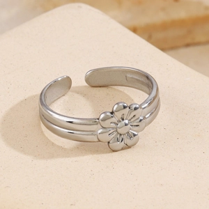 Minimalist silver stainless steel open ring with flower pattern on textured display stand