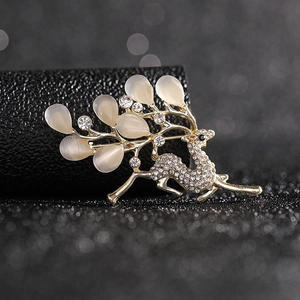 Close-up of golden reindeer brooch with oval opal stones and sparkling rhinestones