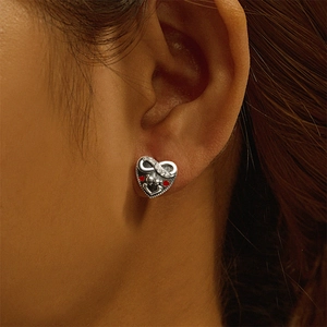 Detail of S925 silver heart earring with infinity symbol and red stones on ear