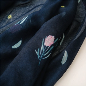 Close-up of navy blue cotton-linen scarf featuring detailed pink floral patterns and texture
