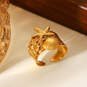 Detailaufnahme von goldenen Seestern- und Muschelanhängern auf einem verstellbaren Ring