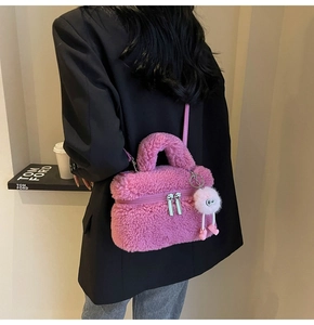 Detailed back view of pink faux shearling crossbody bag with cute plush charm on a model