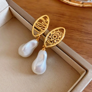Close-up of gold plated hollow metal earrings with white baroque pearl drop pendants