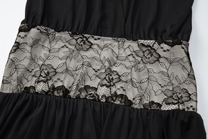 Détail d'une robe noire montrant l'insert de taille en dentelle florale et le tissu doux