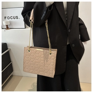 Detail of beige tote bag with 3D geometric texture and elegant gold chain strap