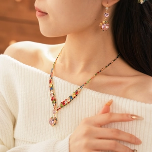 Close-up of model wearing pink heart-shaped crystal pendant necklace and gold earrings