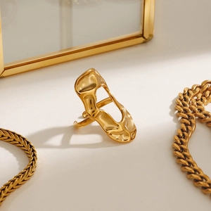 Detailed view of long irregular 18k gold lava ring against a stylish golden mirror