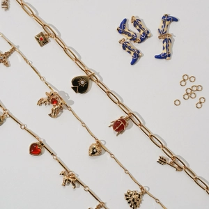 Flat lay of gold DIY jewelry chains with heart charms and blue cowboy boot pendants