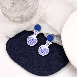 Detail view of blue and white porcelain style vase shaped acrylic drop earrings on felt
