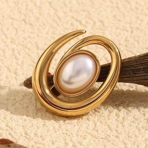Detailed view of 18K gold-plated conch brooch with premium pearl on a rustic wood stand