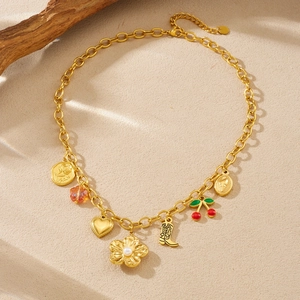 Gold-plated pastoral necklace with cherry, flower, and boot charms on textured background