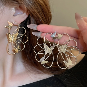 Macro detail of butterfly hollow metal earrings with artistic lines and gold finish