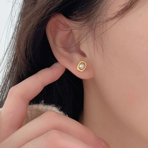 Gros plan de boucles d'oreilles rétro françaises en perles dorées portées à l'oreille