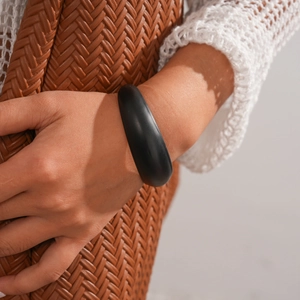 Close-up of minimalist black acrylic geometric open cuff bracelet worn on a wrist