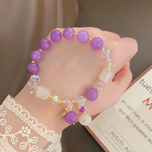 Detail of purple bead bracelet with jade pendant and gold charms on model wrist