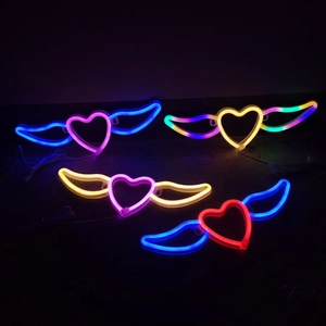 Vue macro de quatre enseignes néon LED cœur ailé colorées sur fond sombre