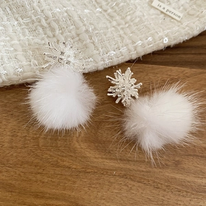 Detail of silver snowflake earrings with white plush pom-pom and sparkling zircons
